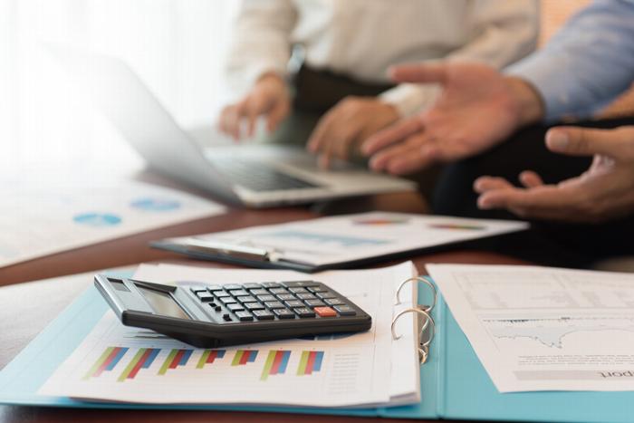 People in a meeting with a laptop and a calculator